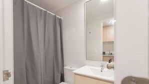 Un baño con inodoro, lavamanos y cortina de ducha.