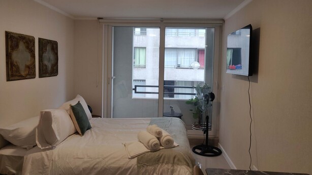 Une chambre d’hôtel avec un lit, une télévision, un balcon et des œuvres d’art accrochées au mur.