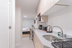 Een compacte hotelkamer met een kitchenette, een bed en een zithoekje.