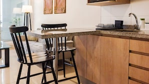 A modern kitchen with wooden cabinets, a granite countertop, and a dining area with chairs and a table. - Santiago: 1BR Apartment with Balcony and Views (Santiago)