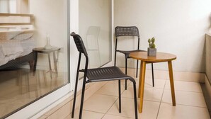 A balcony with a glass door, a small round table, two chairs, and a potted plant. - Santiago: 1BR Apartment with Balcony and Views (Santiago)