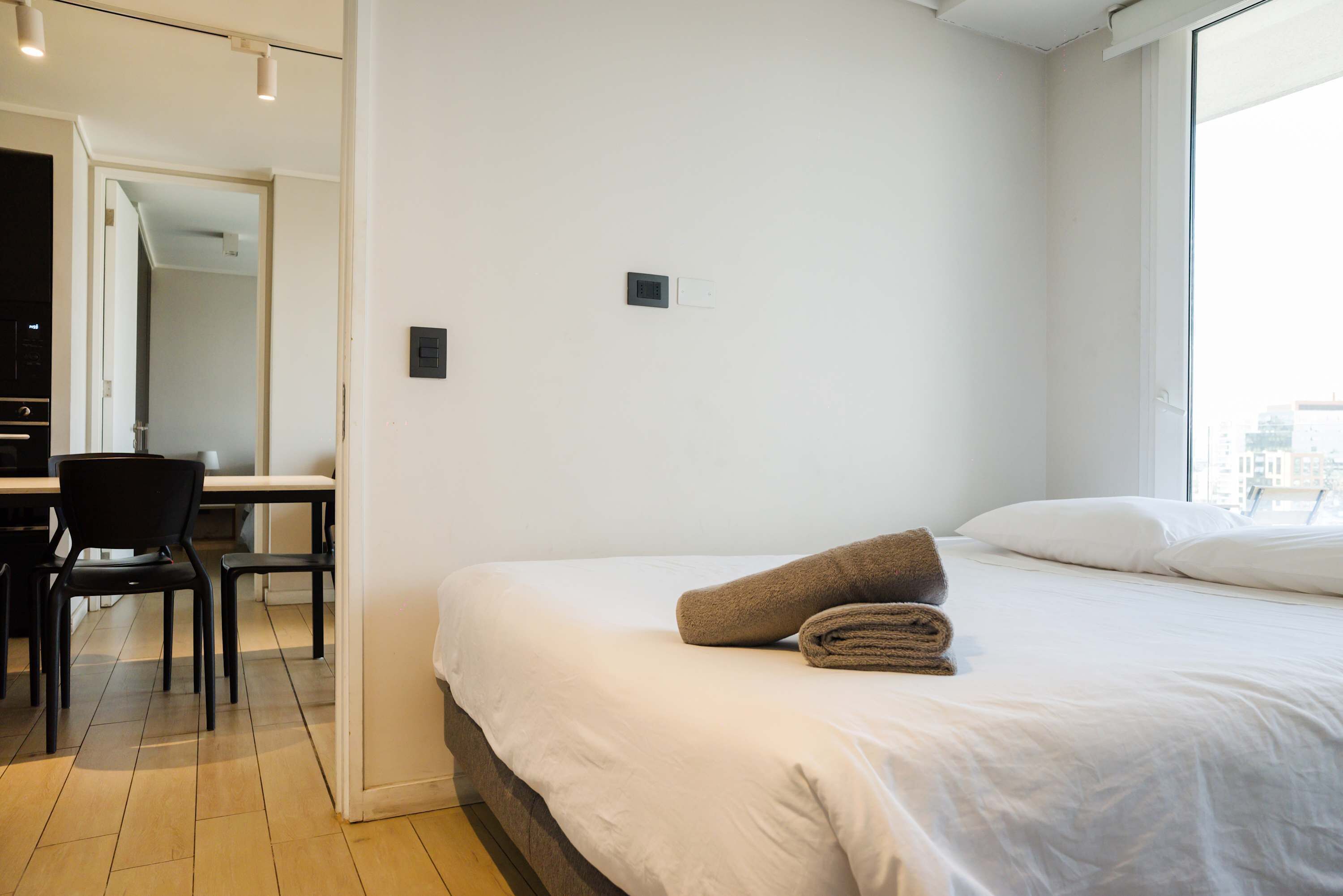 Hotellihuone, jossa on sänky, työpöytä ja tuoleja.