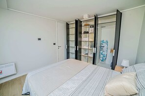 Une chambre à coucher avec un lit, une armoire et une table de chevet avec une lampe.