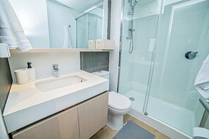 Une salle de bain moderne avec une douche à parois de verre, un lavabo avec un miroir et des toilettes.