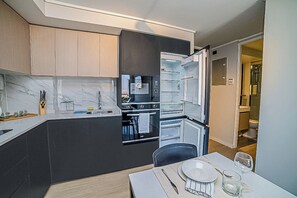 A modern kitchen with dark cabinetry, a built-in oven, and a dining area with a table set for two. - Functional and Bright Apartment in Providencia (Santiago)