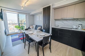 A modern apartment with a dining area, kitchen, and balcony with a city view. - Functional and Bright Apartment in Providencia (Santiago)