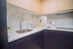 A modern kitchen with dark cabinets, a marble backsplash, and a stainless steel sink.