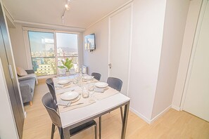 A dining area with a table set for four, a sofa, and a TV on the wall.