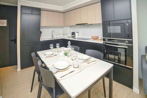 A modern kitchen with a dining table set for four, equipped with a stove, oven, and microwave.