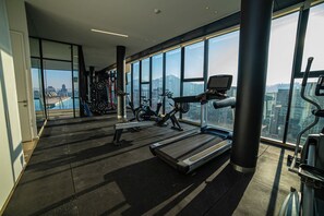 A gym with exercise equipment, large windows, and a city view. - Premium experience in the heart of Providencia (Santiago)