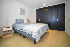 A bedroom with a bed, a bedside table, a wardrobe, and a wall-mounted light fixture. - Premium experience in the heart of Providencia (Santiago)
