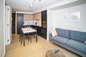 A modern living space with a dining area, kitchenette, and a grey sofa. - Premium experience in the heart of Providencia (Santiago)