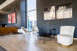 Eine moderne Lobby mit einer Couch, Sesseln, einem runden Tisch und Kunstwerken an der Wand.