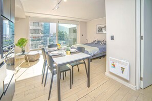 A modern apartment with a dining area, a bed, and a kitchenette.