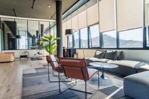A modern living room with a sofa, two chairs, a coffee table, and a large window with a view.