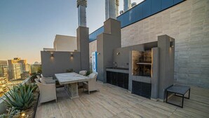 Un patio al aire libre con una mesa de comedor, sillas, una parrilla y una fuente de agua.