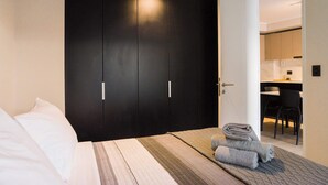 A hotel room with a bed, a large dark wardrobe, and a small table with towels. - Modern 1BR Flat Prime Location Luxury Living (Santiago)