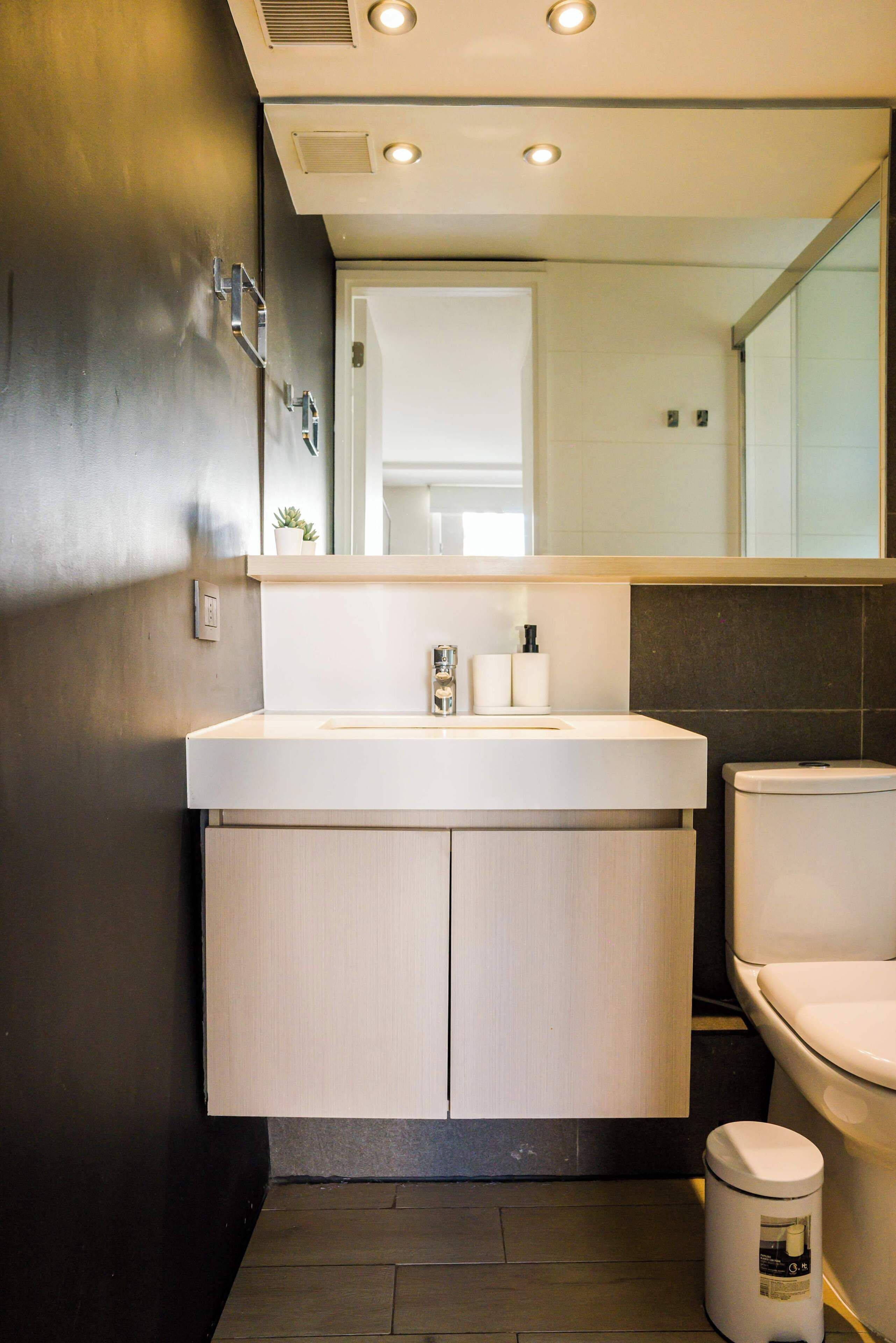 Ein modernes Badezimmer mit Waschbecken, Spiegel und Toilette in Weiß.
