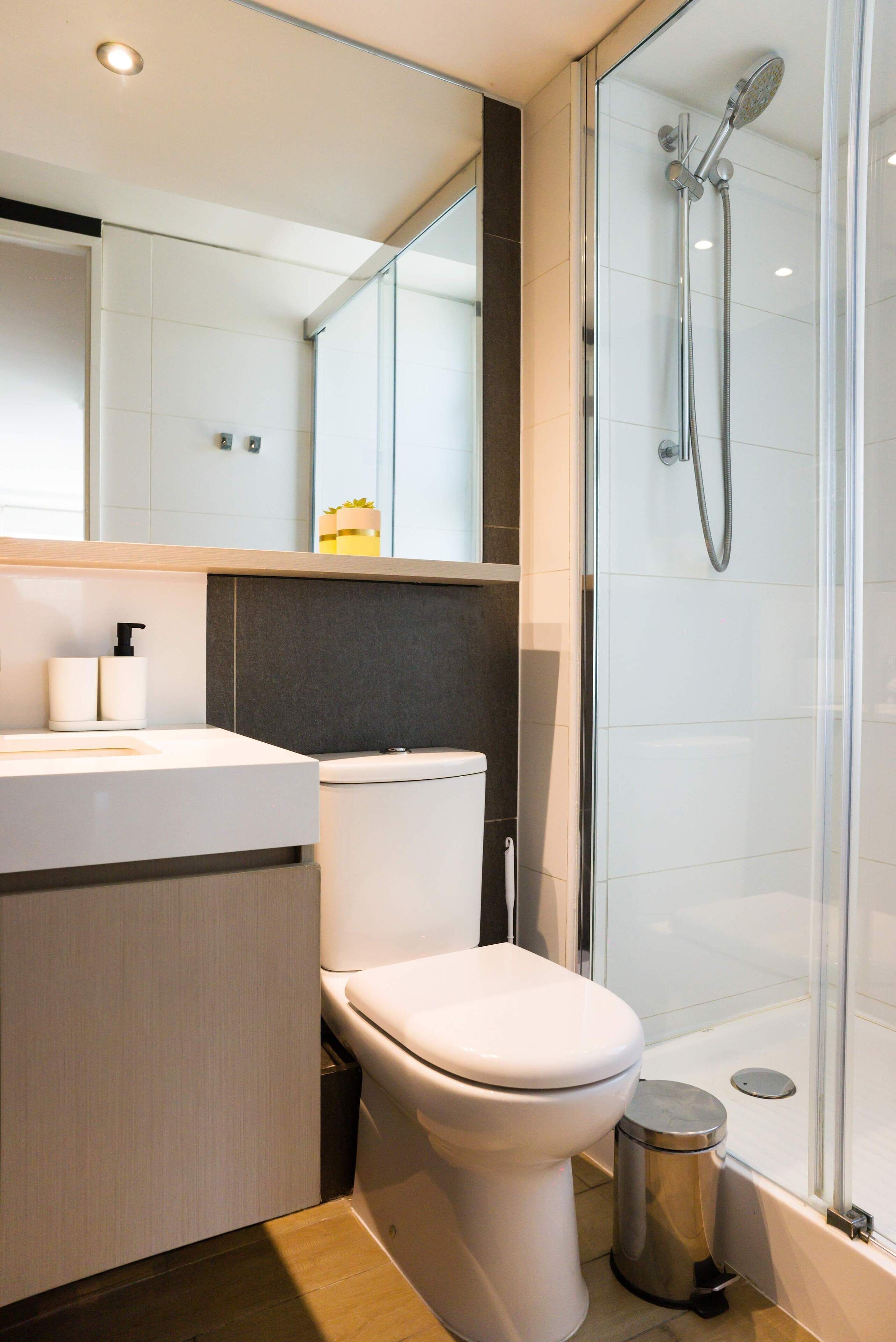 Un baño moderno con inodoro, lavamanos y ducha con cerramiento de vidrio.