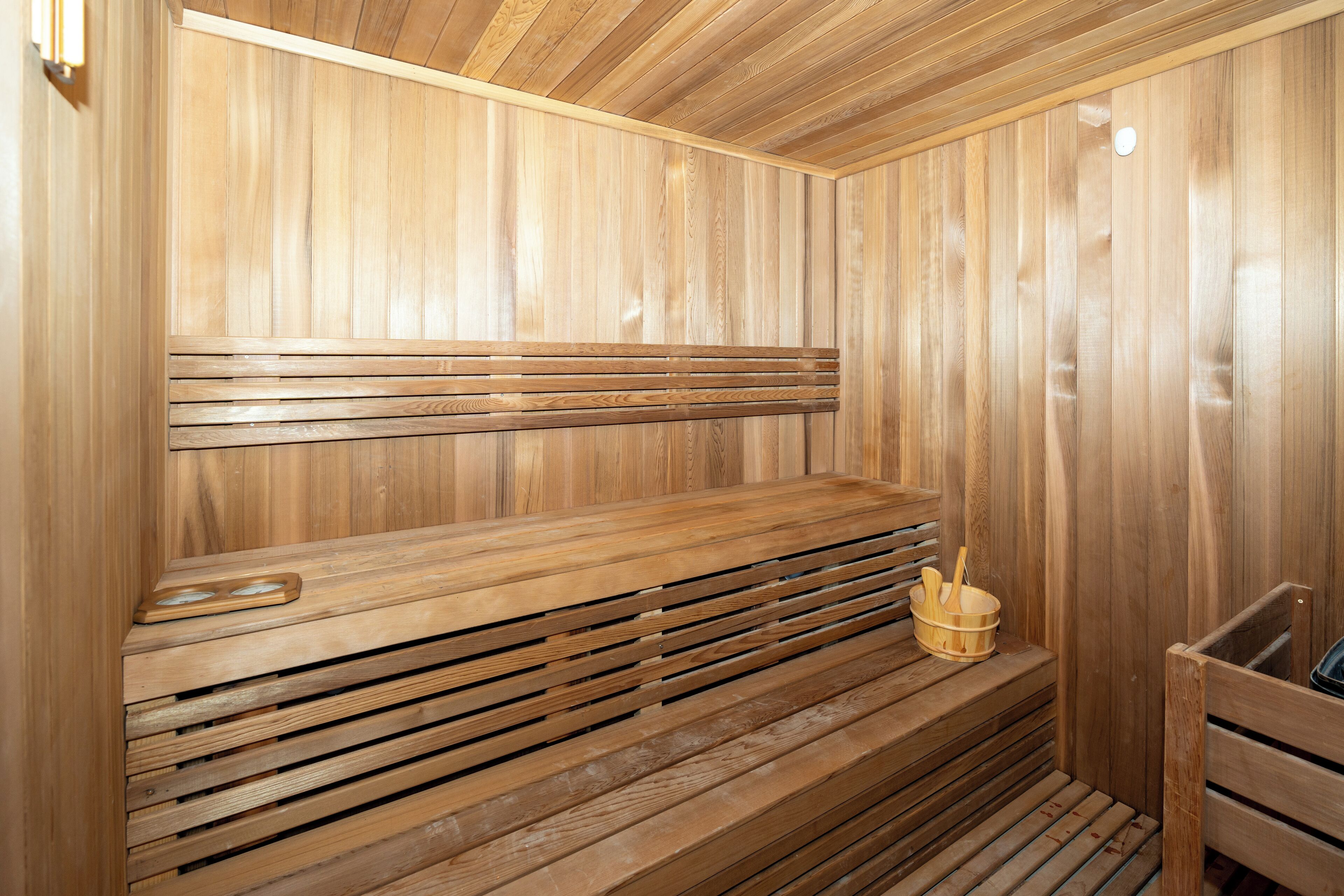 Una sauna de madera con bancos y un cubo de madera.