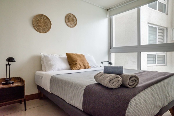 Cozy bedroom with natural light and stylish decor, perfect for relaxation in the heart of the city.
