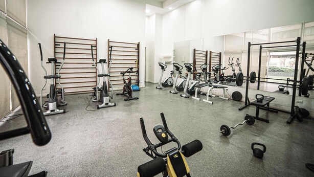 Une salle de sport équipée de divers appareils d’exercice, notamment des tapis de course, des vélos d’appartement et des appareils de musculation.