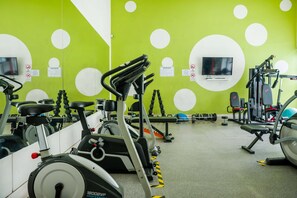 A gym with exercise equipment, a television, and motivational posters on the wall. - Cozy Studio In Vibrant Las Condes | 2 Guests (Las Condes)