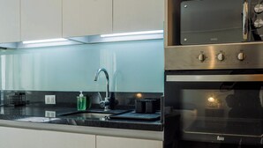 Una cocina con armarios blancos, una estufa de acero inoxidable y un horno.