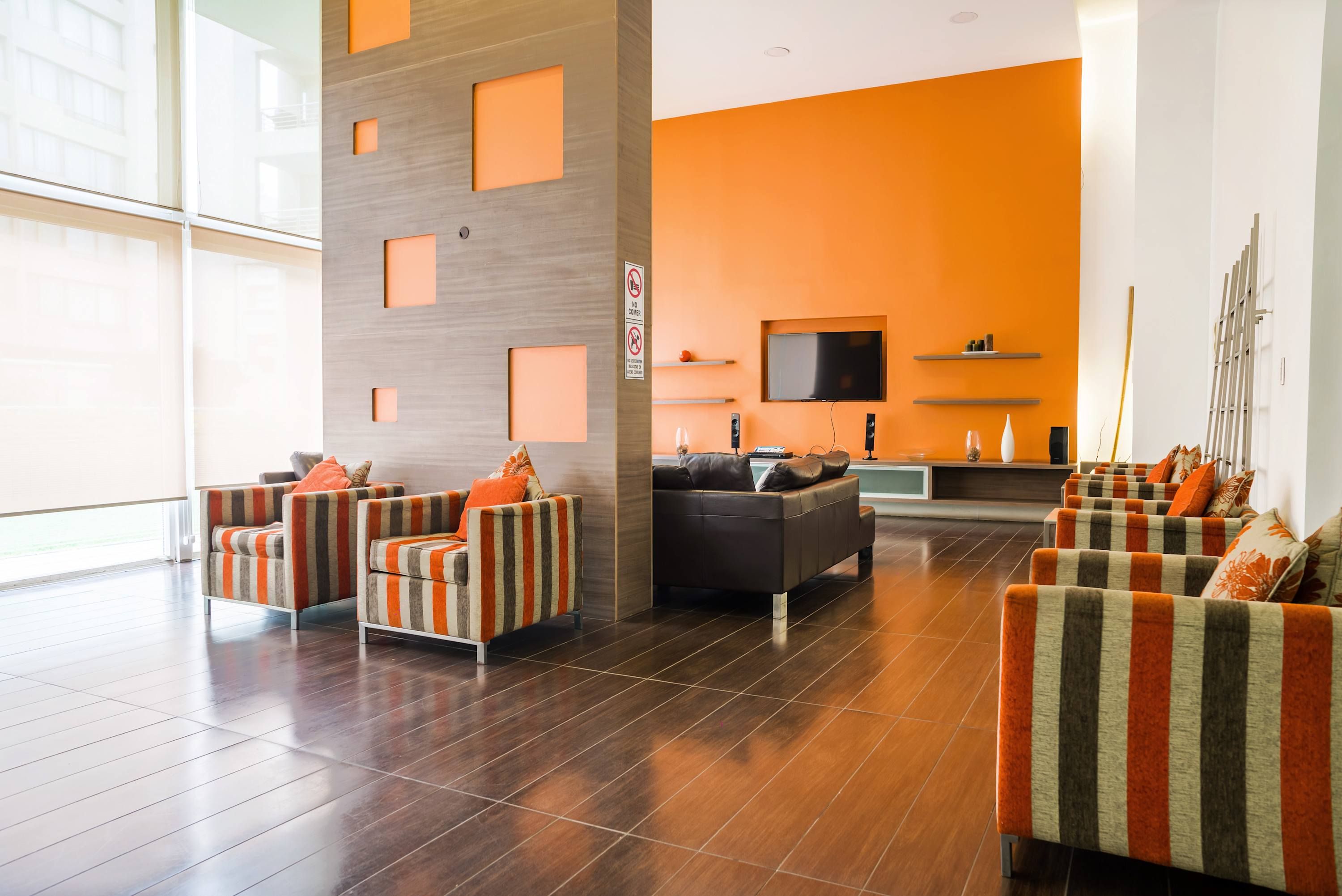 A modern living room with striped sofas, a flat-screen TV, and a wooden accent wall.