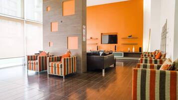 A modern living room with striped sofas, a flat-screen TV, and a wooden accent wall.