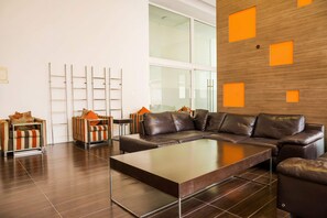 A modern living room with a sectional sofa, a coffee table, and a striped armchair. - Cozy Studio In Vibrant Las Condes | 2 Guests (Las Condes)