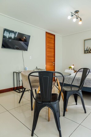 Une chambre d’hôtel avec un lit, un bureau, une chaise, un téléviseur fixé au mur et une porte.
