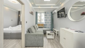 A modern bedroom with a bed, a gray sofa, a small table, and a white cabinet.