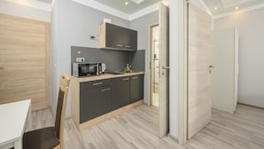 A compact kitchen with dark cabinets, a microwave, and a wooden chair.