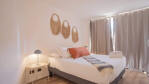 Un letto rifatto con cuscini e coperta, un comodino con una lampada e un elemento decorativo a parete.