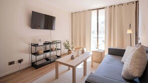 Un soggiorno con una TV a schermo piatto montata a parete, un divano, un tavolino da caffè ed una libreria.