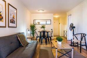 A modern living room with a sofa, dining table, chairs, and a small coffee table.