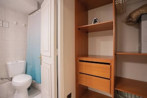 Ein Badezimmer mit Toilette, blauer Duschvorhang und Holzschrank mit Schubladen.