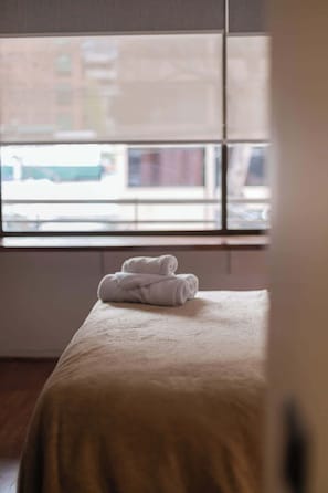 Ein Zimmer mit einem Bett, einem Fenster und Blick auf Gebäude.