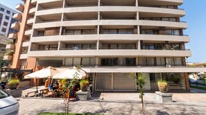 A multi-story building with balconies, outdoor seating, and planters.