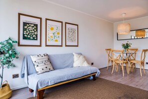 Una sala de estar moderna con un sofá, una mesa de comedor con sillas y tres cuadros en la pared.