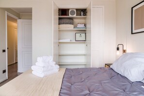 Un dormitorio con una cama, un armario blanco y una mesita de noche.