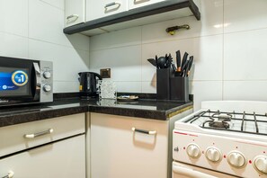 A kitchen with a microwave, coffee maker, and gas stove.