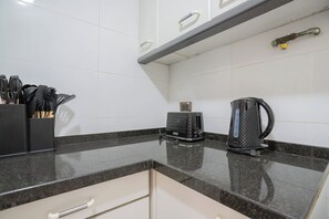 A kitchen with a black countertop, a coffee maker, and a knife block.
