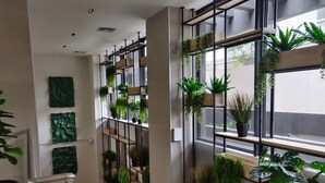 Un interior moderno con una escalera, estanterías metálicas con plantas y un amplio ventanal.