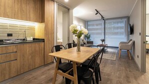 Una cocina moderna con armarios de madera, una mesa de comedor con sillas y un amplio ventanal con vistas a la ciudad.