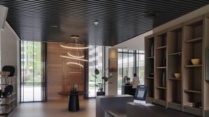 Un área de recepción moderna con un mostrador de madera, una lámpara circular llamativa y un gran ventanal con vistas al exterior.