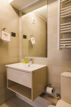 Un baño con lavamanos, espejo, toallero y retrete.