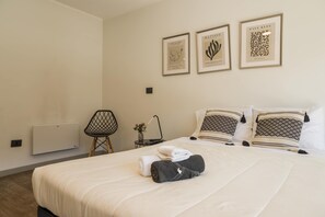 A hotel room with a bed, a chair, a nightstand, and three framed artworks on the wall. - Family Adventure Charming 2BR In Providencia For 5 (Providencia)