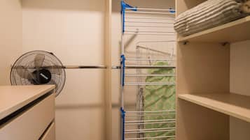 Un armario con estantes, un tendedero y un ventilador.